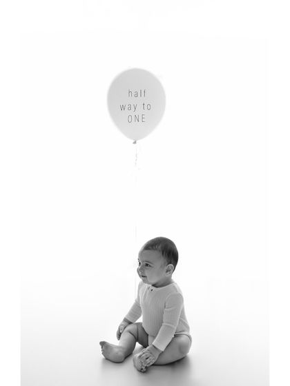A single balloon with the words 'half way to one' adds a simple, celebratory element to this minimalist black and white portrait. It’s a sweet nod to this special milestone.