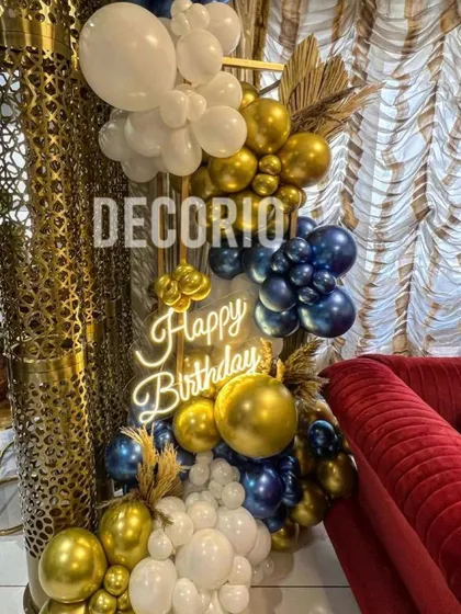 A compact yet luxurious balloon arrangement perfect for a smaller space. This decor features a mix of metallic blue, gold, and white balloons, dried palm leaves, and a neon sign.