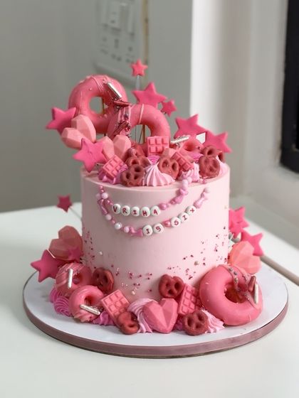 This dreamy pink cake was crafted for Vriha's sixth birthday. It's a perfect example of a loaded cake, adorned with edible beads, stars, donuts, and pretzels for a truly extravagant and fun look.