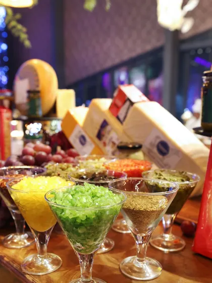 A gourmet cheese and condiment station, featuring a variety of colourful toppings in martini glasses for an elegant and playful presentation.