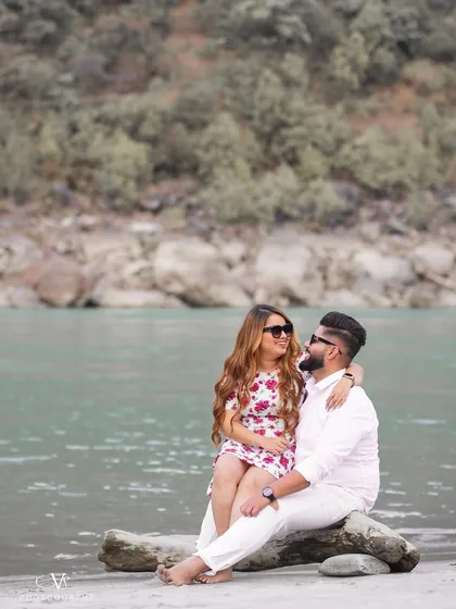 A sweet and relaxed moment from a riverside pre-wedding shoot in Rishikesh, with the couple enjoying the natural scenery.