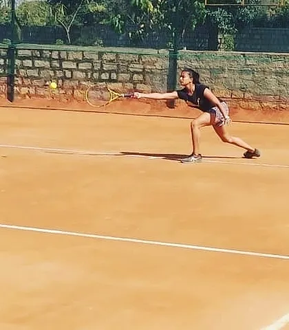 A female competitor lunges for a forehand shot during a UTR tournament, demonstrating focus and determination on the clay court.