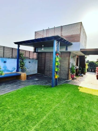 A wide view of the blue pergola, showing how it provides a large, shaded area on this sunny rooftop garden.