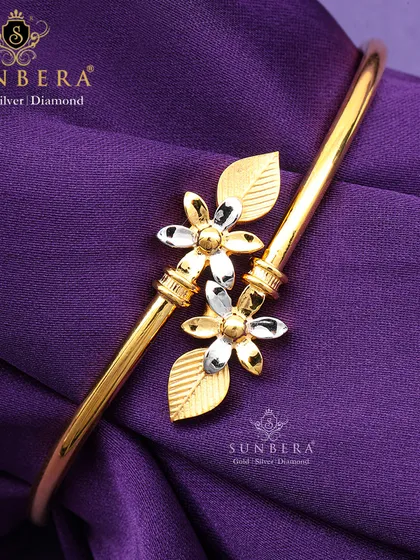 This gold bracelet showcases two delicate flowers with two-tone petals, creating a beautiful contrast. It's a feminine and elegant piece perfect for gifting or personal wear.