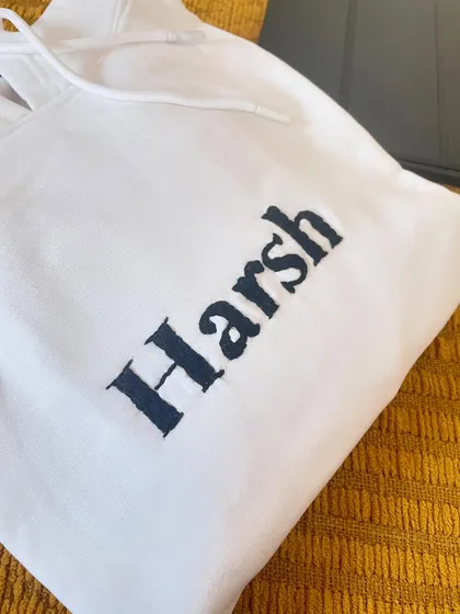 Sometimes simple is best. A clean, bold name 'Harsh' hand-embroidered on the chest of a crisp white hoodie.