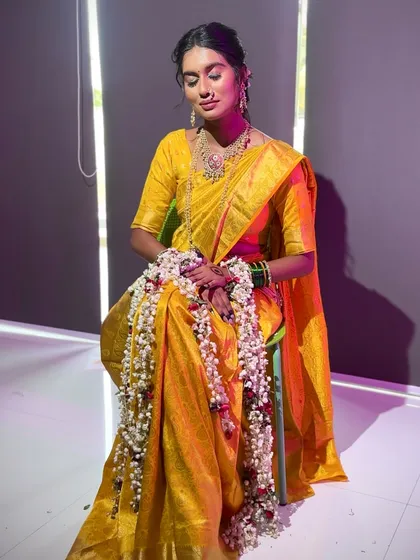 A full-length shot of the bride in her yellow saree, adorned with a long `gajra`, looking serene and beautiful.