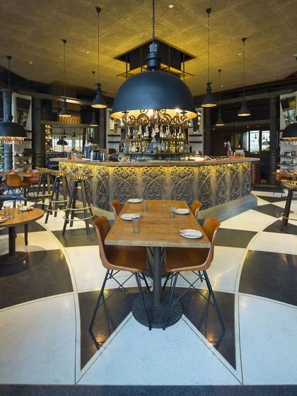 The Townhall restaurant in Gurugram reimagines a public space for interaction and casual meetings. The design is centered around an octagonal bar with a carved wooden front and a dramatic, oversized industrial pendant light.