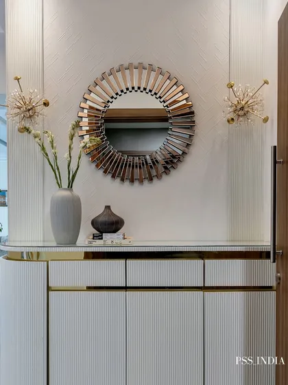 A statement mirror can function as a piece of art. This sunburst-style mirror, paired with starburst sconces and a fluted console, creates a glamorous and welcoming entryway vignette.