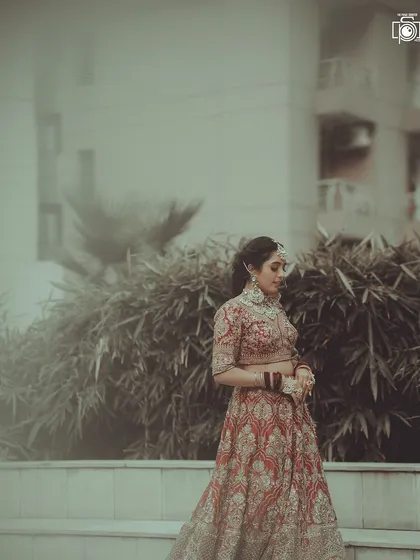 A full-length shot showing the bride in her magnificent lehenga. The soft, hazy filter gives this outdoor portrait a dreamy and romantic quality.