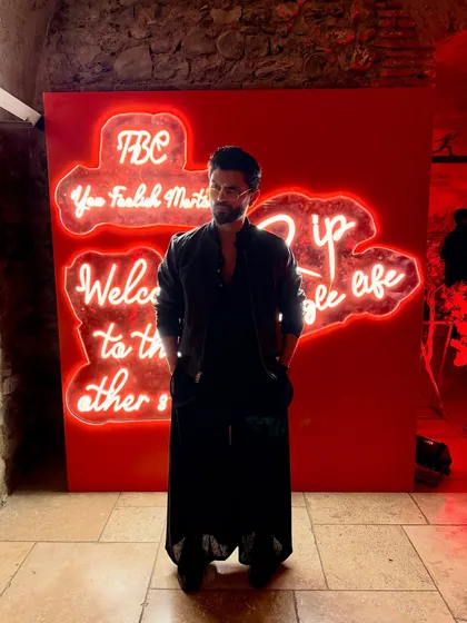 Posing in front of a neon sign, the red light complementing my all-black outfit.