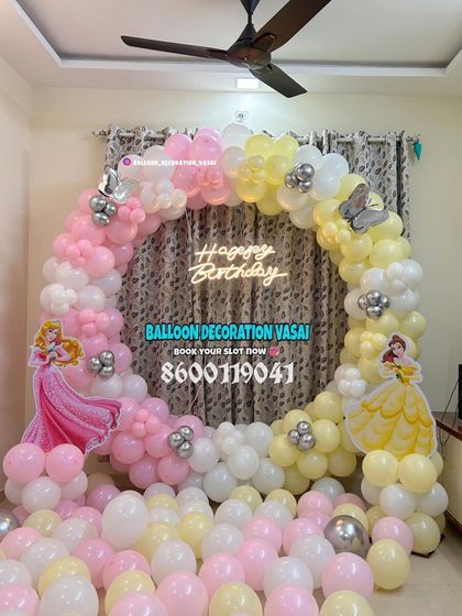 A Belle and Sleeping Beauty princess theme. The ring backdrop is decorated with a soft yellow and pink balloon arch.
