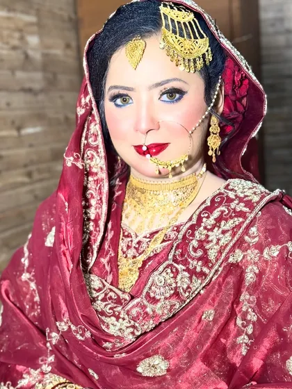 A stunning portrait of an HD Nikkah bride. Her bright blue eyes are beautifully contrasted with the warm tones of her makeup and the traditional red and gold of her attire.