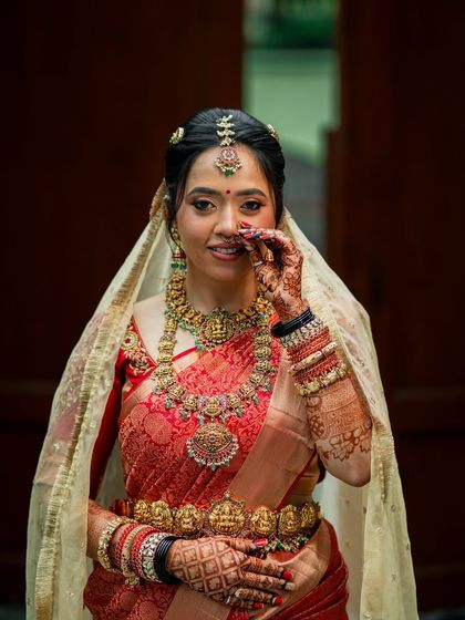 A playful, candid moment, showing the intricate details of her jewellery and the flawless makeup.