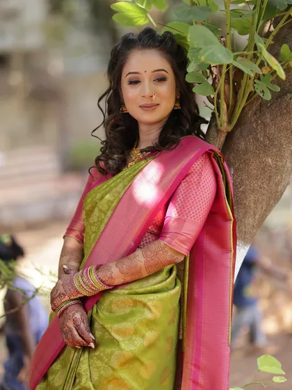 A candid moment under a tree, her makeup looking fresh and natural in the outdoor light.