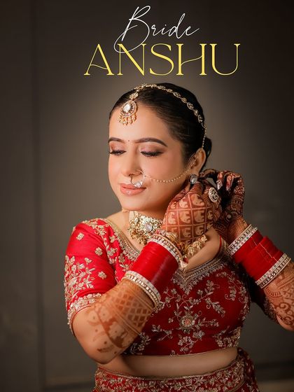 A classic bridal portrait of bride Anshu. She is captured adjusting her earring, a graceful pose that showcases her intricate henna, red bangles, and beautiful jewelry.