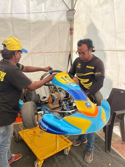 Mechanics working on a kart in the pits.