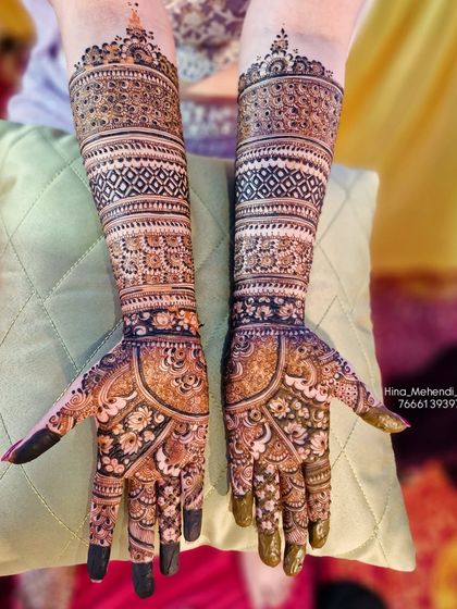 A very detailed and dense bridal mehendi design. The pattern is packed with fine lines, checks, and floral motifs, providing full coverage with a rich, dark stain.