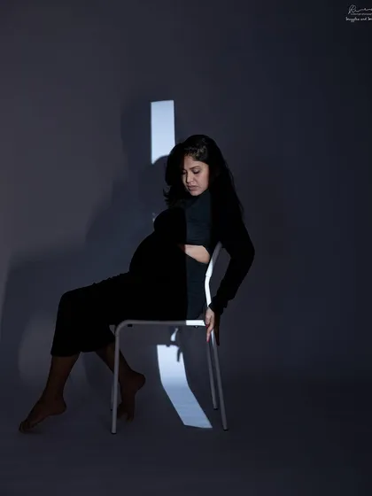A seated portrait using projected light to create strong diagonal lines. This is a very artistic and modern approach to maternity photography.