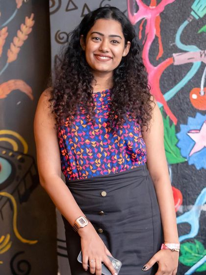 A guest with curly hair, smiling for the camera.