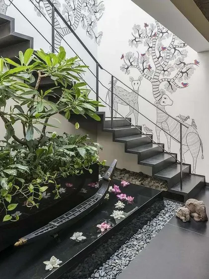 I love finding creative ways to bring nature indoors. This design integrates a tranquil water feature and a planter bed directly under the staircase, turning a forgotten space into a stunning and peaceful art piece with floating flowers.