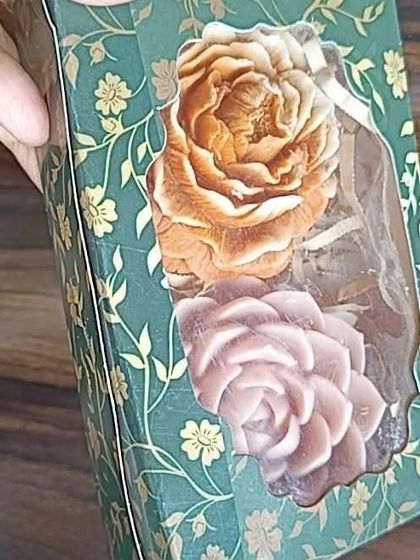 This decorative floral box is being used to package two large rose-shaped soaps or candles. It's a beautiful and sturdy option for gifting.