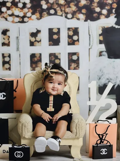 A full view of the fun and stylish shopaholic-themed set. This little one is surrounded by her favorite brands, showing off her big smile.