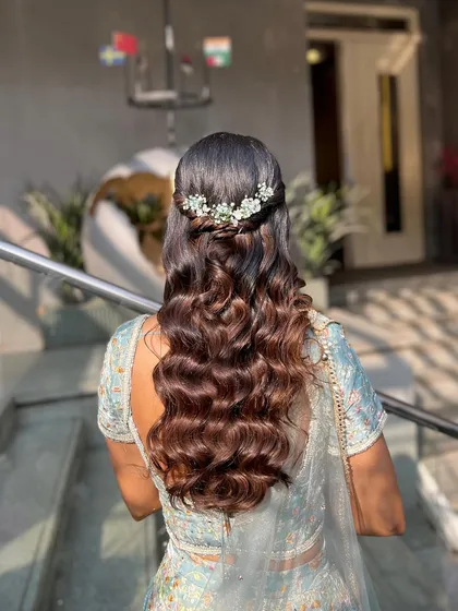A view of the elegant half-up hairstyle with a beautiful floral accessory, completing this romantic engagement look.