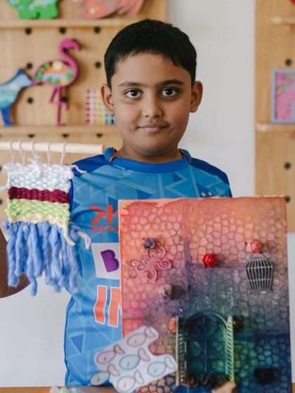 Another proud artist from our summer camp, holding his woven creation and a textured mixed-media piece. My camps are all about exploring different art forms and finding what excites you.