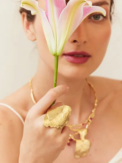 A close-up on a statement ring. The lily adds a touch of organic beauty and draws the eye to the hand.