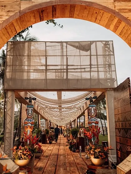 An entrance should be a portal to another world. For this 'Bora Bora' themed celebration, I designed a striking circular wooden gateway, immediately immersing guests in a tropical paradise and setting the stage for the exotic experience within.