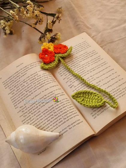 A closer look at the flower bouquet bookmark inside a book. The vibrant orange and yellow flowers bring a touch of nature to your reading time.