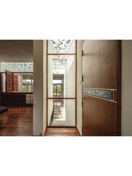A detail of the wooden flooring and door in the Cube Square house, showing the custom stained-glass inlay that echoes the leaf motif of the skylight.