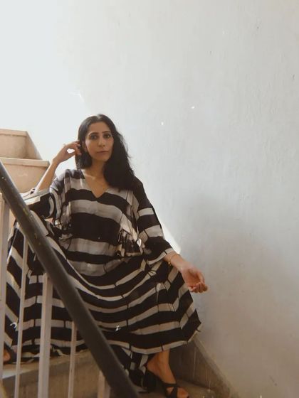 A full-length shot on a staircase for House of Wandering Silk, showcasing the beautiful flow and silhouette of the dress.