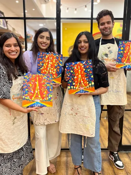 Four friends proudly showing off their colorful Eiffel Tower paintings. It's a fun and creative way to spend an afternoon together.