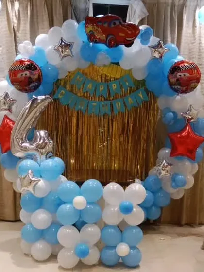 A 'Cars' movie themed ring decoration for a 4th birthday, using blue and white balloons and a Lightning McQueen foil balloon.