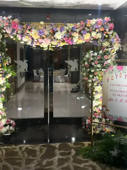 A grand entrance for a 75th birthday celebration, with a lush arch of pastel-colored flowers welcoming guests.
