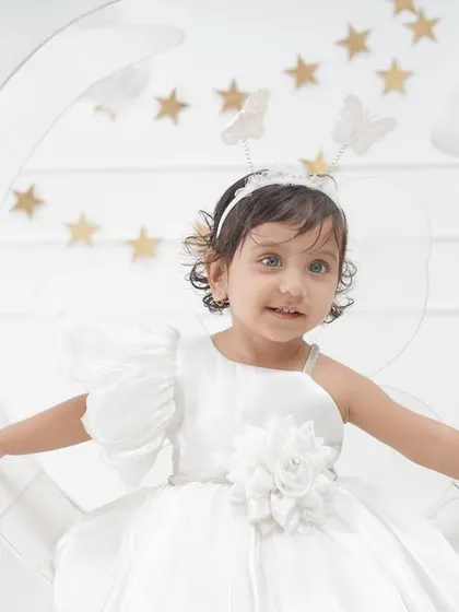 A close-up from the 'Moon & Stars' session, capturing the little girl's sweet smile and her ethereal white dress and butterfly headband.