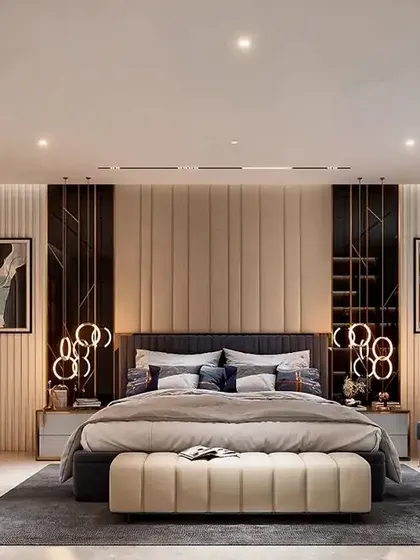 A luxurious master bedroom with a grand, upholstered headboard and elegant wall paneling. The design incorporates sophisticated lighting, including track lights and bedside pendants, to create a layered and inviting atmosphere.
