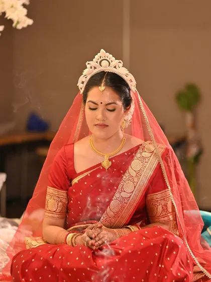 A moment of quiet reflection during the ceremony. The makeup looks soft and natural even in the warm, ambient light.