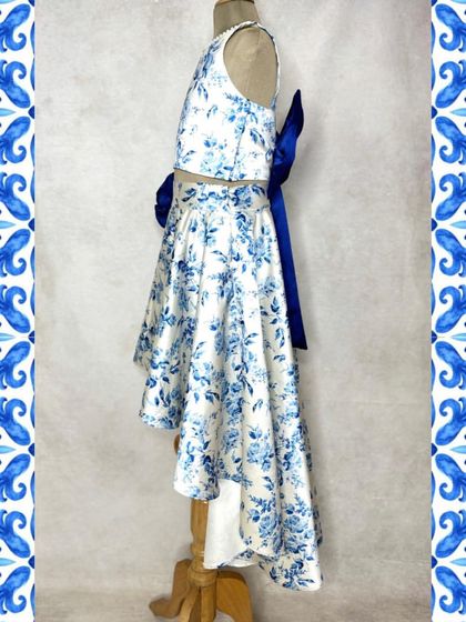 The perfect brunch outfit. This beautiful blue and white floral print set features a high-low skirt and a matching crop top, with a stunning statement bow at the back.