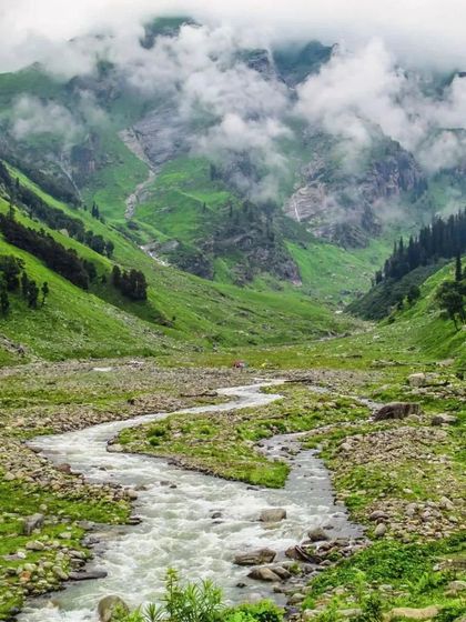 The winding river making its way through the Hampta Pass valley, a picturesque landscape.