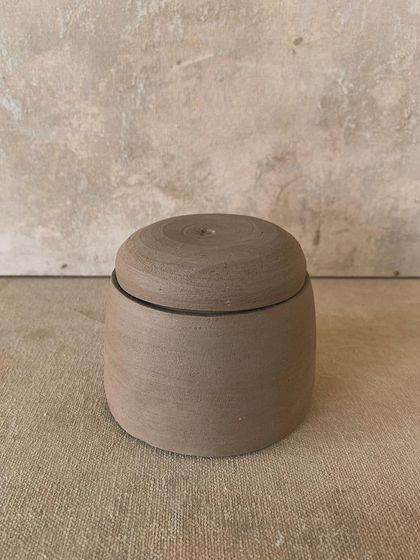 A simple, elegant lidded jar in its raw, unfired state. The form is clean and the fit of the lid is precise, showcasing a student's growing skill on the wheel.
