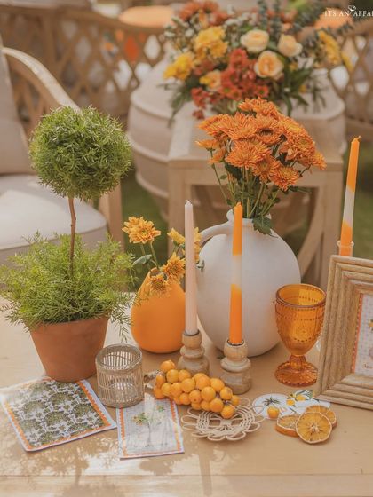 More tabletop details, including orange-hued glassware, candles, and fresh kumquats, all contributing to the citrus theme.