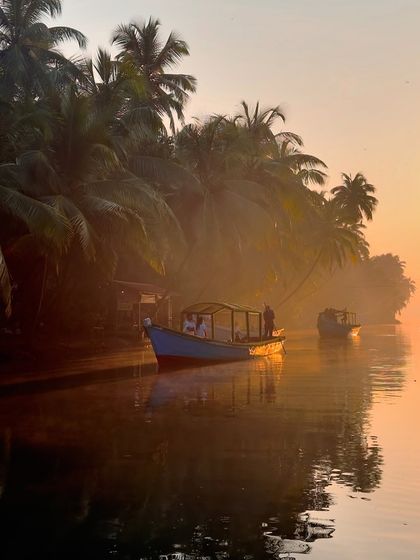 The magical light of the golden hour reflecting on the water, with boats and palm trees creating a classic coastal scene.