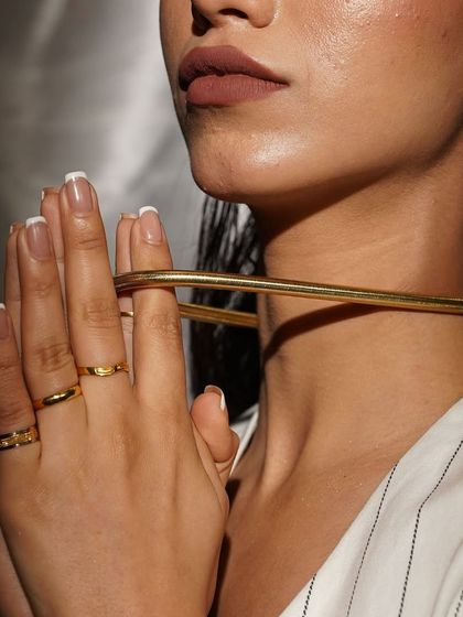 A moment of quiet elegance, featuring our bold gold choker and a stack of delicate rings.