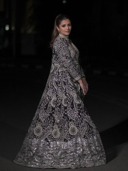 A full-length view of this dramatic sangeet look. The makeup is strong enough to balance the heavily embellished black and silver gown, creating a powerful and cohesive statement.