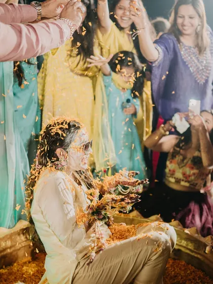 The bride enjoying her Haldi ceremony, showered with love and marigold petals by her family and friends. It's a beautiful ritual filled with blessings and joy.
