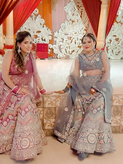 Two friends looking beautiful in their rented pastel lehengas. One is in a pink and silver piece, and the other in a grey floral one.
