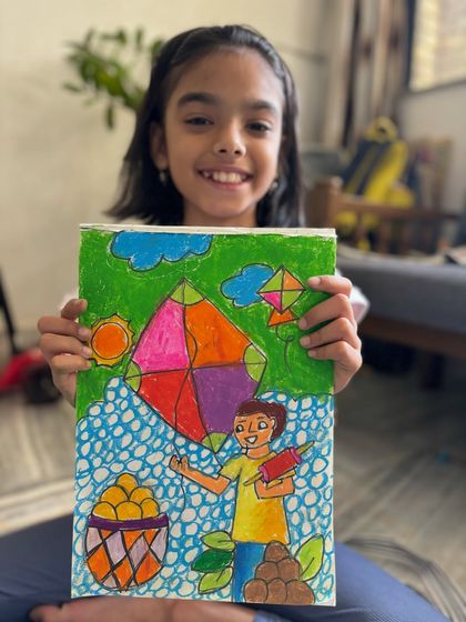A happy student displays her intricate Makar Sankranti artwork, complete with kites, sweets, and a cheerful atmosphere. We incorporate many festive elements into our drawings.