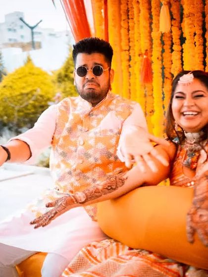 A candid shot of the couple laughing during their Mehendi ceremony, showcasing their genuine happiness and the relaxed atmosphere.